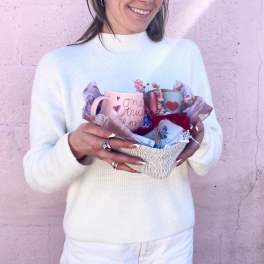 Woman holding a gift basket with two mugs and tissue paper