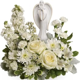 White floral arrangement with an angel figurine in the center