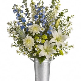 White lilies and blue delphinium in a silver bucket vase