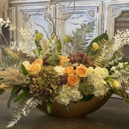 Large floral centerpiece with orange roses and white hydrangeas in a low bowl