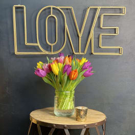 Bouquet of multicolored tulips in a glass jar on a table