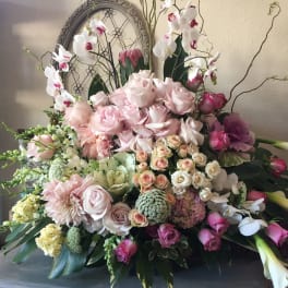 Large pastel floral arrangement with roses, orchids, and calla lilies