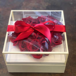 Red roses in a clear gift box tied with a red ribbon