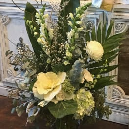 Tall floral arrangement with pale yellow blooms in a glass vase
