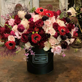 Large bouquet of red, pink, and cream roses in a black hatbox