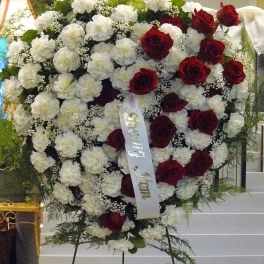 Heart-shaped standing spray of red roses and white carnations on an easel