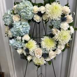 Heart-shaped floral wreath with blue hydrangeas, white roses, and pale chrysanthemums