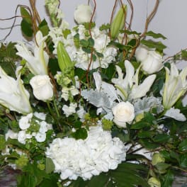 Large white floral arrangement with lilies, roses, and hydrangeas