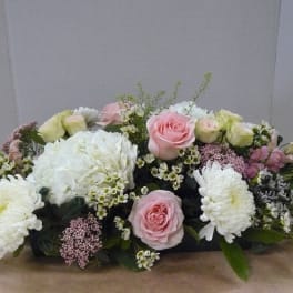Low floral centerpiece with pink roses, white hydrangeas, and white chrysanthemums