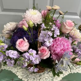 Basket arrangement of pink and lavender flowers with roses and chrysanthemums