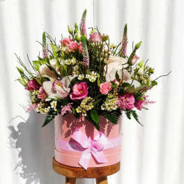 Pink and white mixed flower arrangement in a round pink box with ribbon