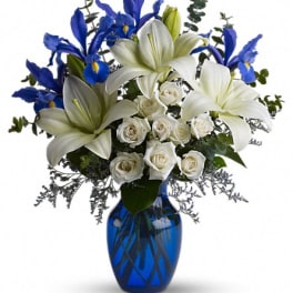 White lilies and roses with blue irises in a cobalt vase