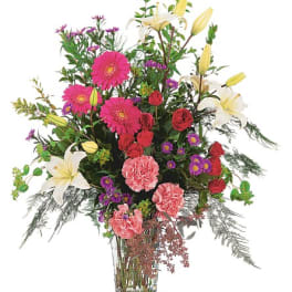 Tall mixed bouquet with lilies, gerbera daisies, roses, and carnations in a glass vase