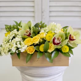 Yellow roses and white orchids in a wooden box arrangement