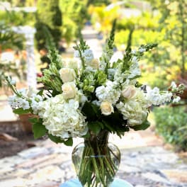 White roses and hydrangeas arranged in a clear glass vase