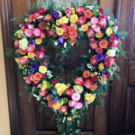 Heart-shaped floral wreath on a stand with multicolored roses
