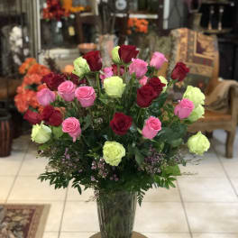 Bouquet of pink, red, and lime roses in a clear glass vase