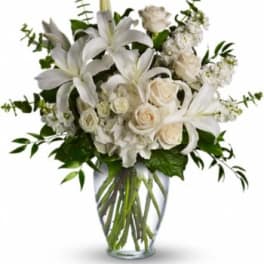 White lilies and roses arranged in a clear glass vase