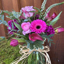 Pink and magenta bouquet in a blue glass vase with raffia bow