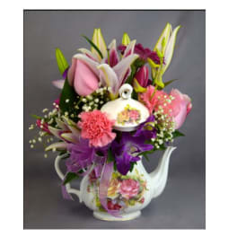 Bouquet of pink and purple flowers in a floral teapot vase