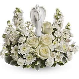 White floral arrangement with roses and a praying angel figurine