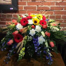 Large mixed floral arrangement with red, yellow, white, and coral blooms