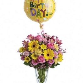 Birthday balloon above a mixed bouquet in a glass vase