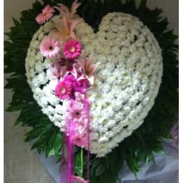 Heart-shaped white floral wreath with pink flowers and ribbon accents