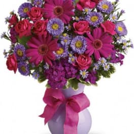 Pink and purple mixed bouquet in a lavender vase with a ribbon