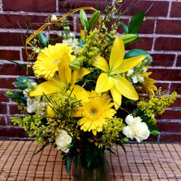 Yellow lilies and gerbera daisies in a glass vase