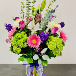 Mixed bouquet with pink roses, lilies, gerbera daisies, and hydrangeas in a glass vase