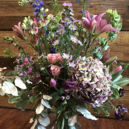 Mixed bouquet of pink lilies, roses, and hydrangea in a glass vase