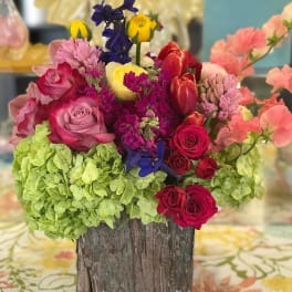 Colorful mixed flower arrangement in a rustic wooden container