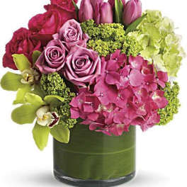 Pink roses, tulips, hydrangea, and orchids in a glass vase