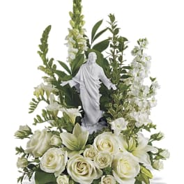 White floral arrangement with a small religious statue in the center