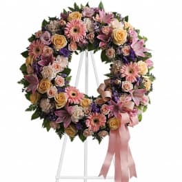 Floral wreath with pink and peach flowers on a white stand