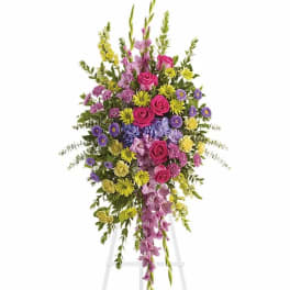 Tall standing floral spray with pink roses and purple flowers on an easel