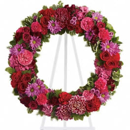 Circular wreath of red, pink, and purple flowers on a white stand