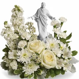 White floral arrangement with a statue of Jesus in the center