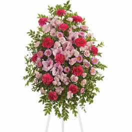 Standing floral spray of pink and red flowers on a white easel