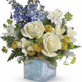 Blue and white floral arrangement in a glass cube vase