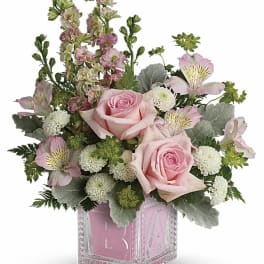 Pink roses and mixed blooms arranged in a clear pink glass vase