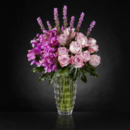 Pink roses and purple orchids in a clear glass vase