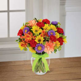 Colorful mixed bouquet in a clear glass vase with a green ribbon