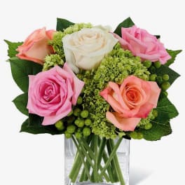 Bouquet of pink, peach, and white roses in a clear glass vase