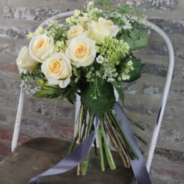 Bouquet of cream roses with small white filler flowers and a ribbon