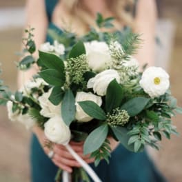 Bride holding a white bouquet with greenery