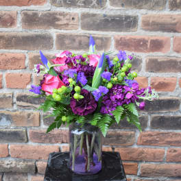 Pink and purple flower arrangement in a glass jar vase