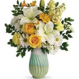 Yellow roses and white lilies in a green ceramic vase