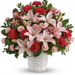 Pink lilies and carnations in a white woven basket
